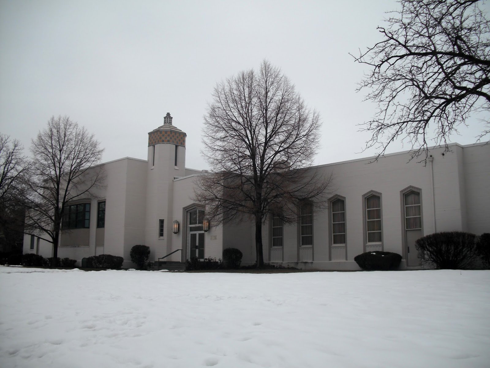 Exterior of the Yalecrest Chapel in Salt Lake City, an Art Deco–style Latter-day Saint meetinghouse with tall narrow windows and a patterned tower, photographed in winter with snow covering the ground.