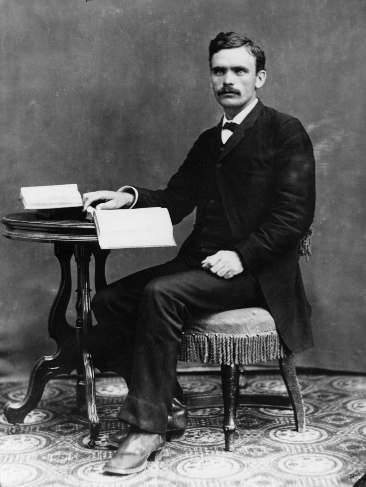 A photograph portrait of Brigham Henry (B. H.)  Roberts sitting to study some books sometime in the late 1800s.