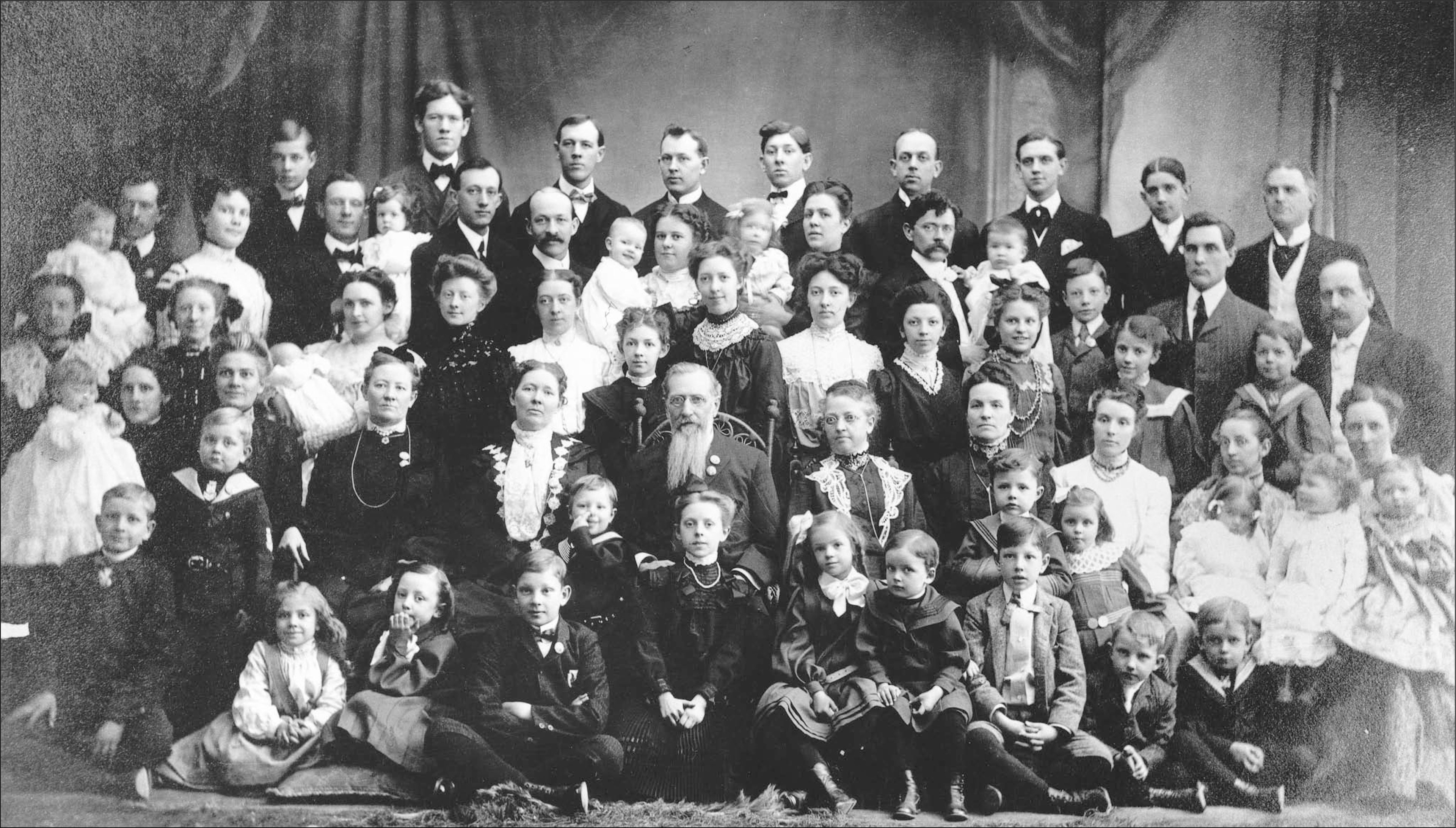 Family photograph of Joseph F. Smith, his five wives, and most of their children taken in 1904. Middle row, from left to right: Mary Taylor Schwartz, Edna Lambson, Julina Lambson, Joseph F. Smith, Sarah Ellen Richards, and Alice Ann Kimball.