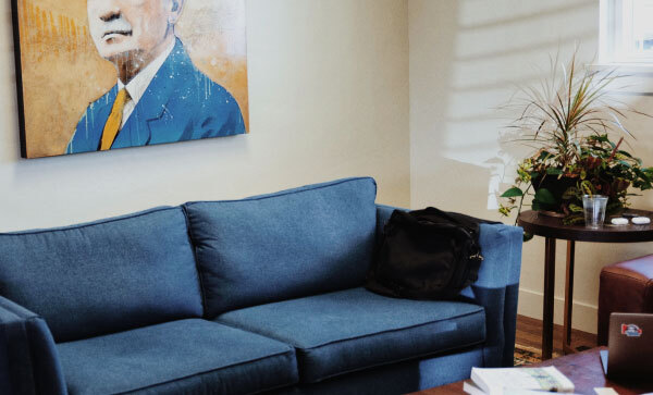 Office space featuring a portrait of B. H. Roberts, a blue couch, and tables holding assorted items. 