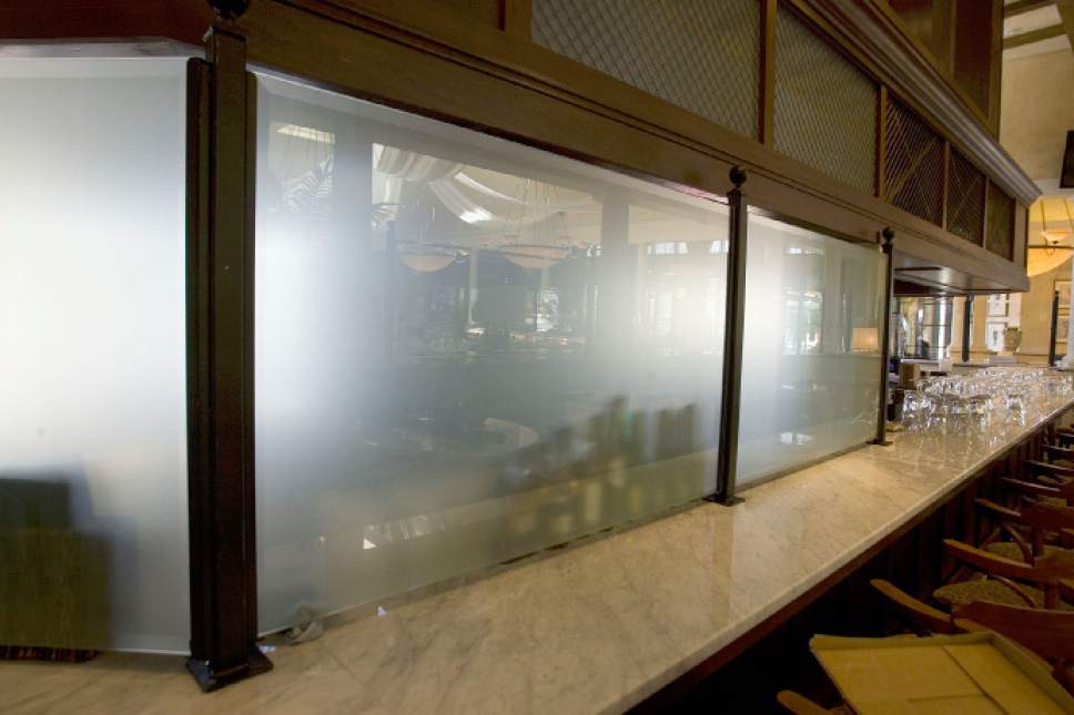 A photograph of a bar with a Zion Curtain, a large translucent glass barrier to prevent customers from seeing drinks being mixed.