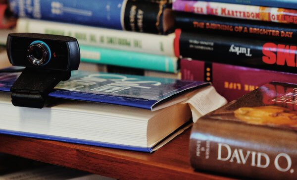 Close-up van een tafel bedekt met boeken over het mormonisme, waarvan er één wordt gebruikt als standaard voor een webcam.
