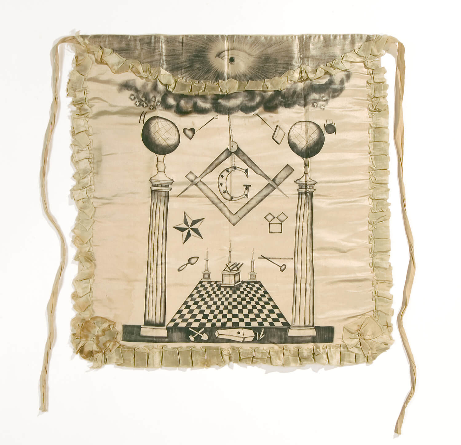 A photograph of an off-white silk Masonic apron belonging to Joseph Smith, covered in hand painted symbols of freemasonry, from circa 1842-1844.